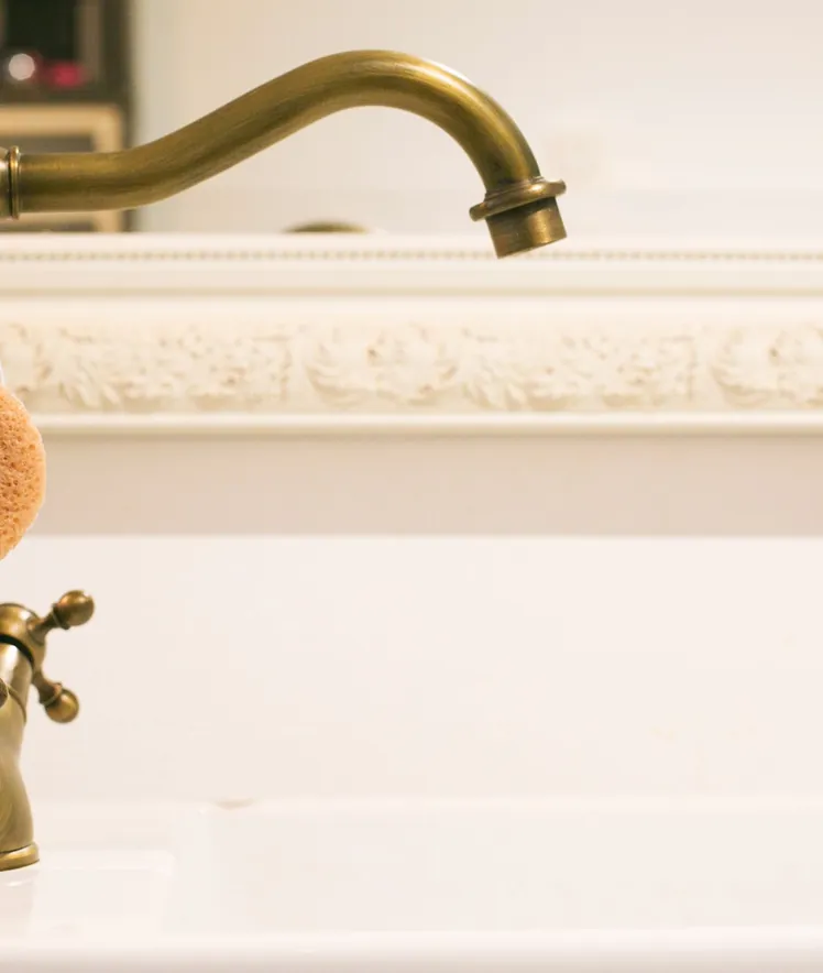 A brass kitchen tap over a white sink